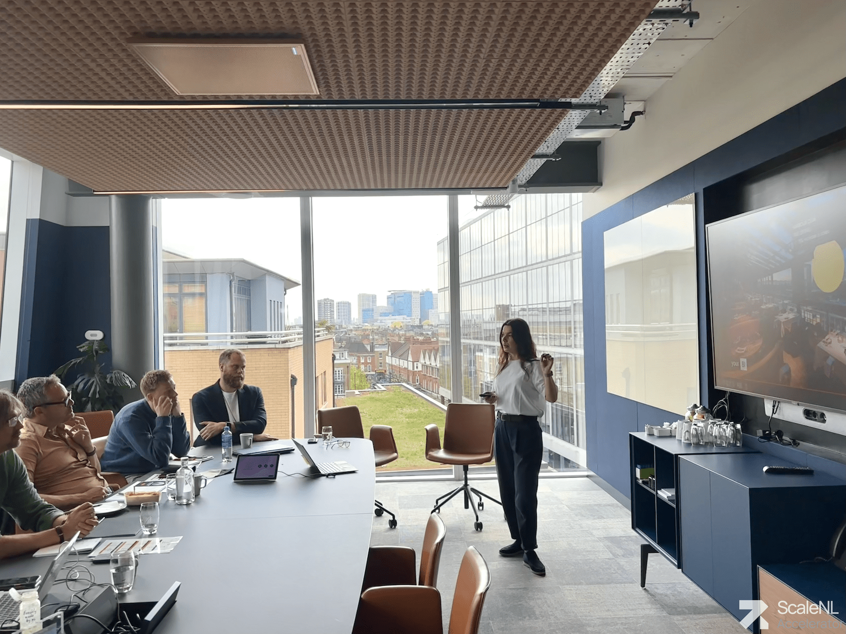 Female founder pitching in front of a small jury in an office room